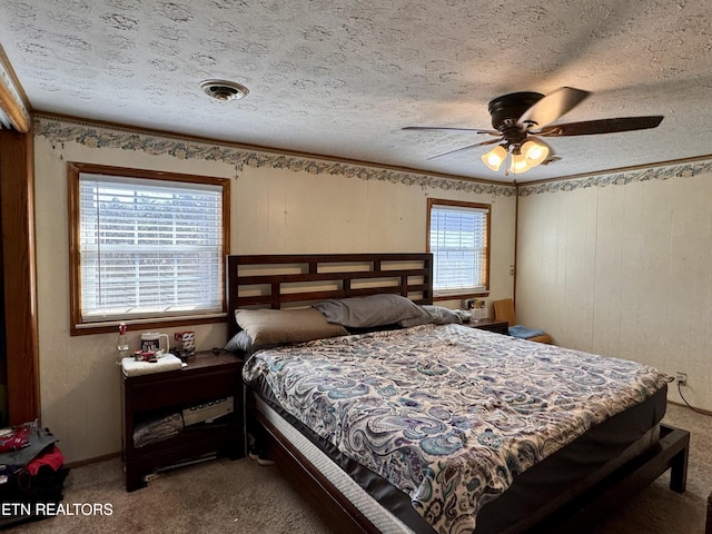 carpeted bedroom featuring crown molding, ceiling fan, multiple windows, and a textured ceiling