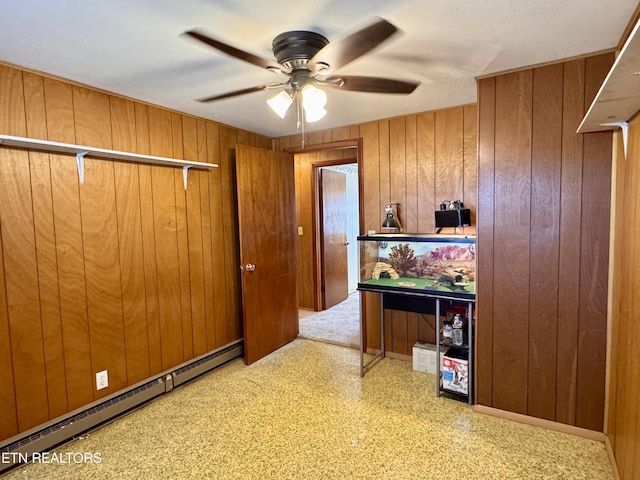 interior space with a baseboard radiator, ceiling fan, and wood walls