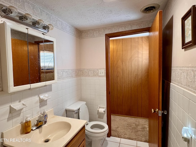 bathroom with tile walls, vanity, tile patterned floors, and a textured ceiling