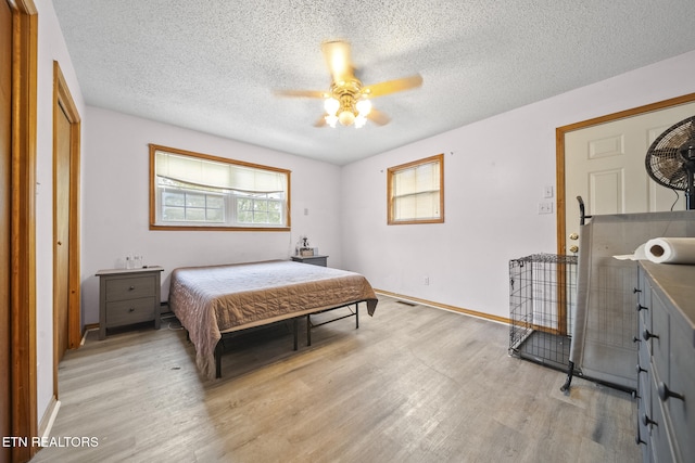 bedroom with ceiling fan, light hardwood / wood-style floors, and a textured ceiling