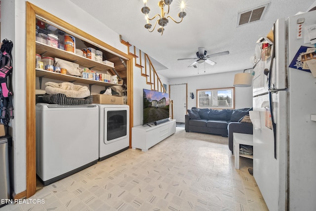 laundry room featuring ceiling fan with notable chandelier, washer and dryer, and a textured ceiling