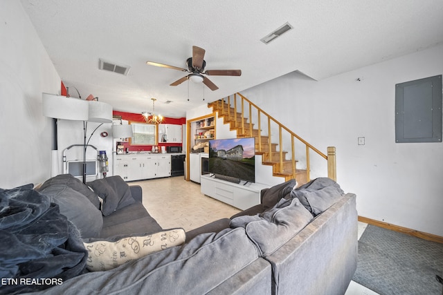 living room featuring electric panel, ceiling fan with notable chandelier, and a textured ceiling