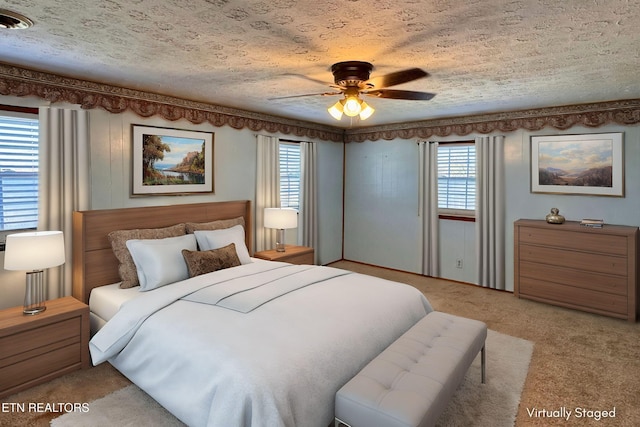 carpeted bedroom featuring ceiling fan, multiple windows, and a textured ceiling