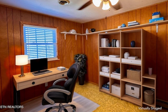 office area with ceiling fan and wood walls