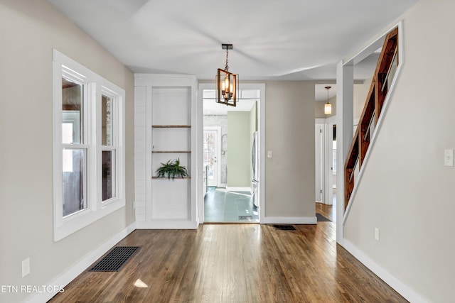 foyer with dark wood-type flooring and an inviting chandelier