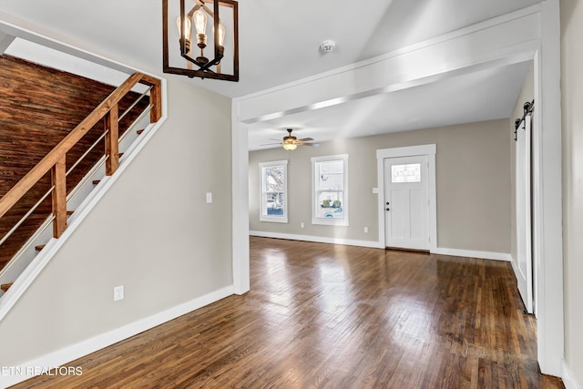 foyer entrance featuring a barn door, dark hardwood / wood-style floors, and ceiling fan with notable chandelier