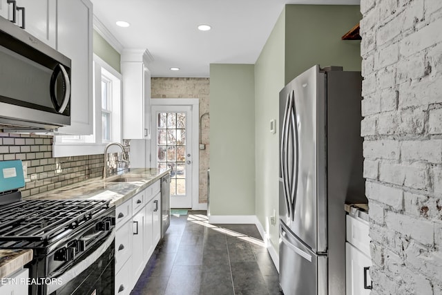 kitchen featuring appliances with stainless steel finishes, light stone countertops, sink, and white cabinets