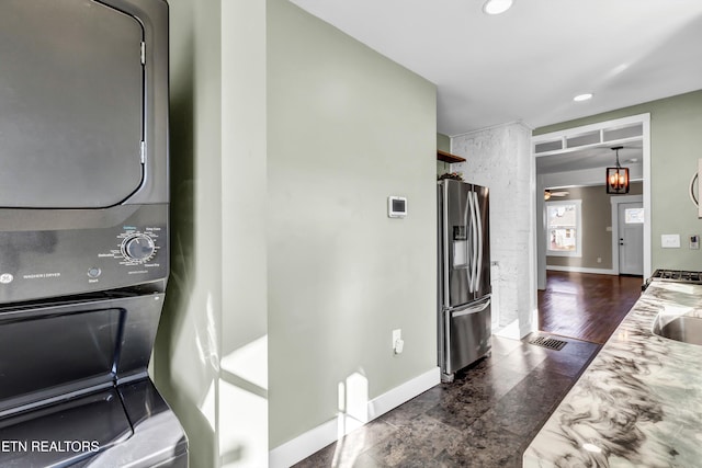 interior space featuring sink, stainless steel fridge, and stacked washer and clothes dryer