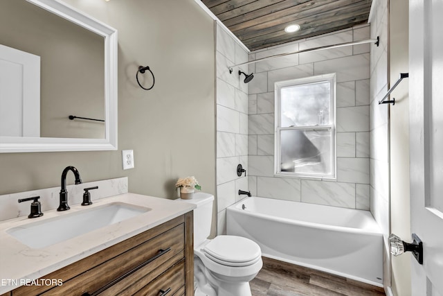 full bathroom featuring wood-type flooring, tiled shower / bath combo, vanity, toilet, and wooden ceiling