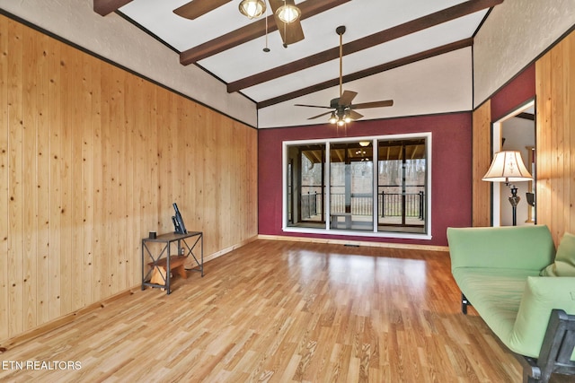 unfurnished room featuring vaulted ceiling with beams, wood-type flooring, wooden walls, and ceiling fan