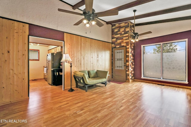 sitting room with lofted ceiling with beams, light hardwood / wood-style flooring, and wood walls