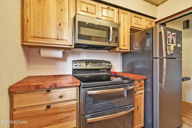 kitchen featuring stainless steel appliances, wood counters, and light hardwood / wood-style floors