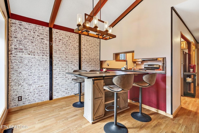 bar featuring stainless steel appliances, pendant lighting, light hardwood / wood-style floors, and beam ceiling