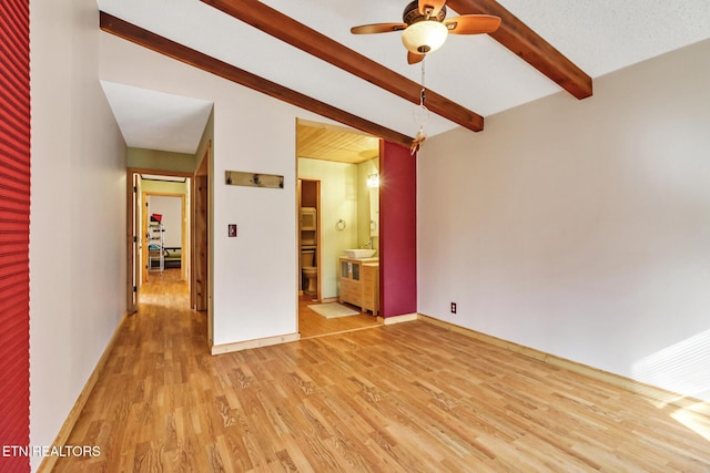 unfurnished room featuring ceiling fan, light hardwood / wood-style flooring, and beamed ceiling