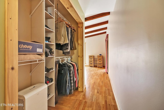 walk in closet with hardwood / wood-style floors and beam ceiling