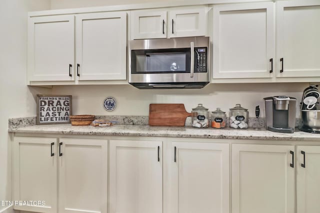 kitchen featuring white cabinetry and light stone countertops