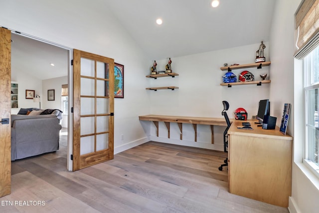 home office featuring vaulted ceiling, a wealth of natural light, and light hardwood / wood-style flooring