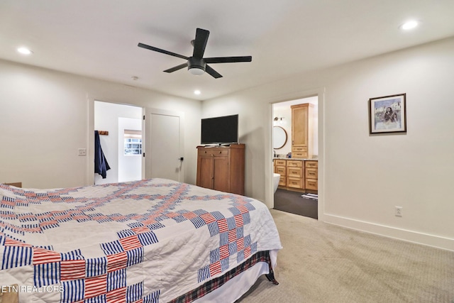 bedroom with ensuite bathroom, light carpet, and ceiling fan