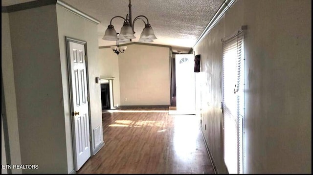 hall with dark wood-type flooring, a textured ceiling, crown molding, and a chandelier