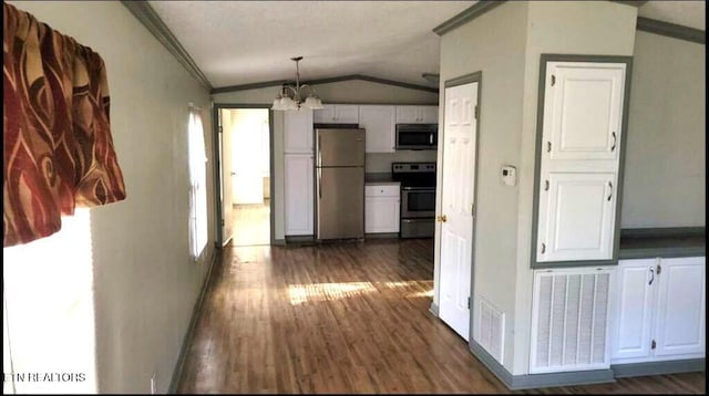 kitchen with white cabinets, lofted ceiling, decorative light fixtures, stainless steel appliances, and a chandelier