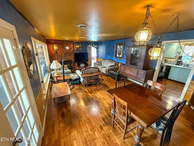 dining area with wood-type flooring and brick wall