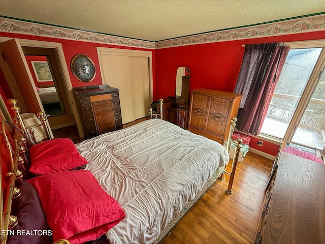 bedroom with wood-type flooring, multiple windows, and a textured ceiling