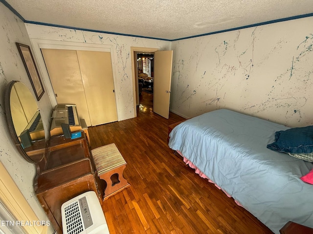 bedroom with crown molding, dark wood-type flooring, a textured ceiling, and a closet