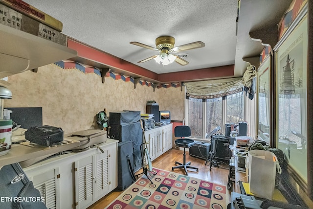 office featuring a textured ceiling, light wood-style flooring, and a ceiling fan