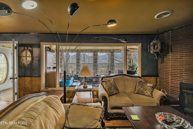 living area featuring brick wall, visible vents, and wood finished floors