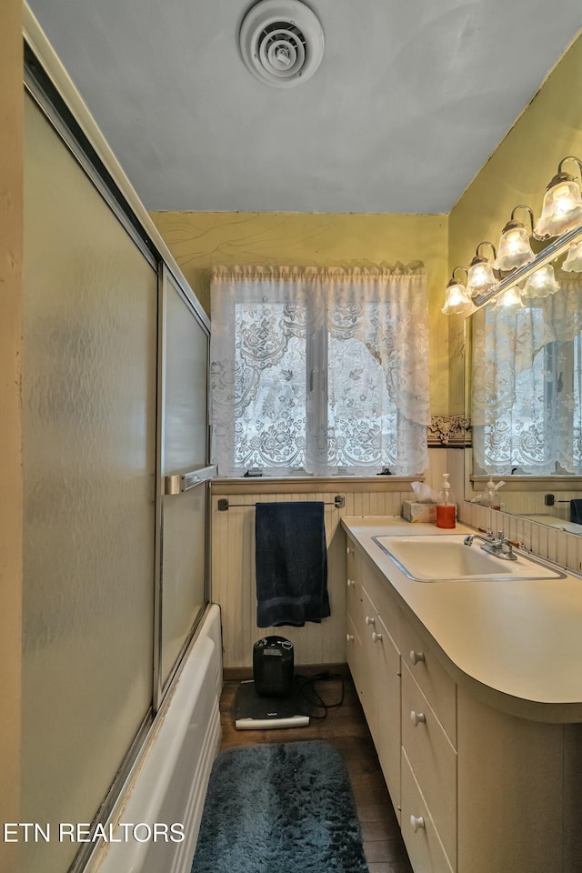 full bathroom featuring enclosed tub / shower combo, vanity, wood finished floors, and visible vents