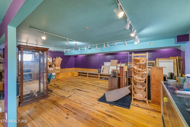 interior space with wainscoting, hardwood / wood-style flooring, and track lighting