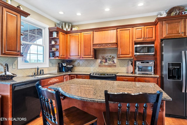 kitchen with sink, a kitchen island, light stone countertops, and appliances with stainless steel finishes