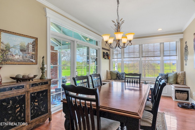 dining space featuring light hardwood / wood-style flooring, a notable chandelier, crown molding, and a wealth of natural light