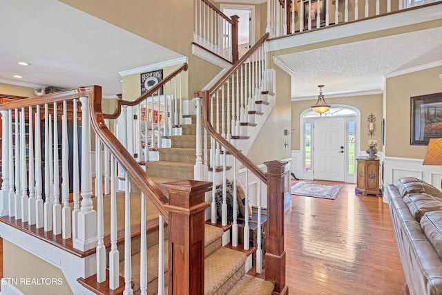 foyer with ornamental molding, hardwood / wood-style floors, and a textured ceiling