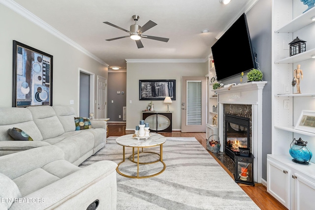 living room featuring ceiling fan, crown molding, a premium fireplace, and light wood-type flooring