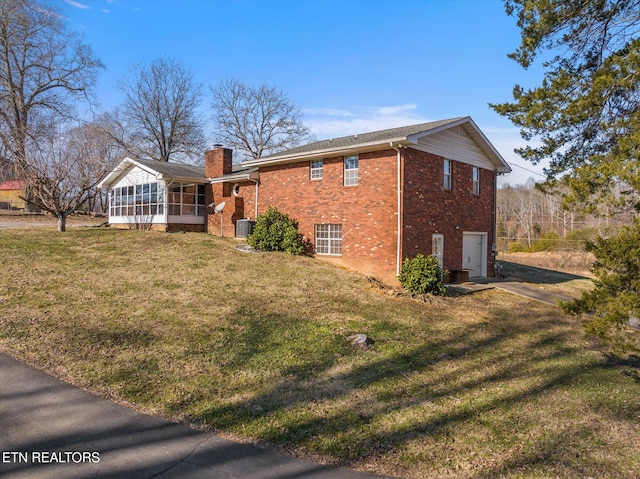 view of side of property featuring a garage, a yard, and a sunroom