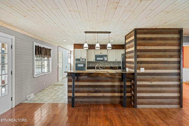 kitchen with decorative light fixtures, tasteful backsplash, sink, wood ceiling, and black appliances