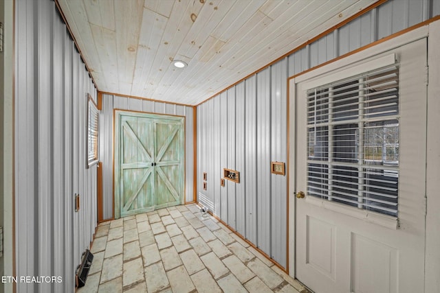 interior space with ornamental molding, wooden ceiling, and wood walls