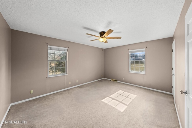 unfurnished room with a wealth of natural light, light carpet, a textured ceiling, and ceiling fan