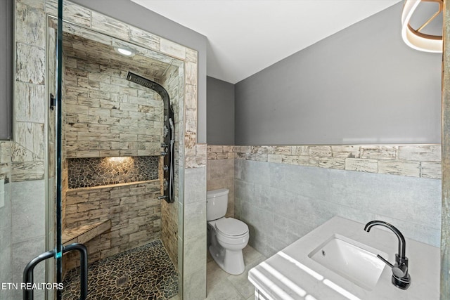 bathroom with toilet, an enclosed shower, sink, and tile walls