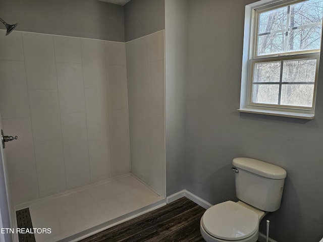 bathroom featuring hardwood / wood-style flooring, toilet, and a tile shower