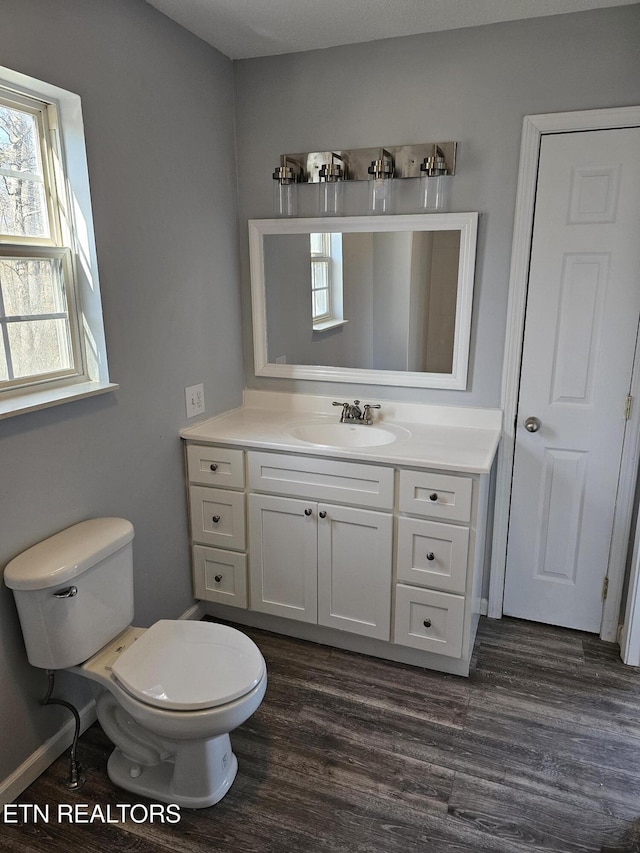 bathroom featuring vanity, wood-type flooring, toilet, and a healthy amount of sunlight