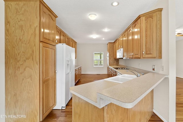 kitchen with kitchen peninsula, sink, hardwood / wood-style floors, white appliances, and a kitchen bar