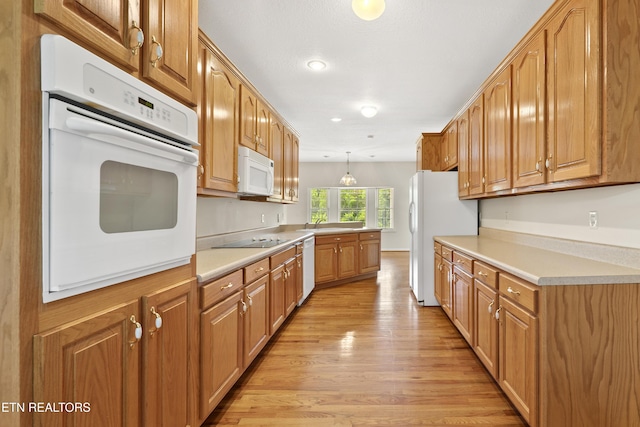 kitchen featuring sink, decorative light fixtures, white appliances, and light hardwood / wood-style flooring