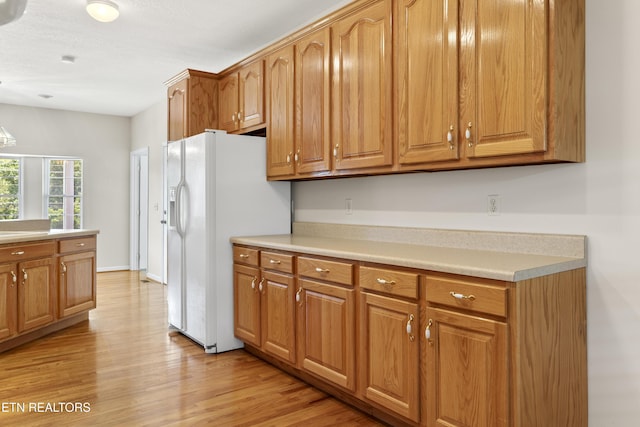 kitchen with white refrigerator with ice dispenser and light hardwood / wood-style floors