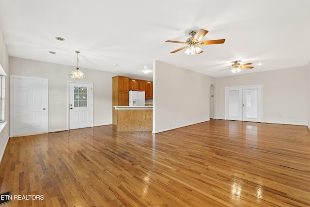 unfurnished living room with ceiling fan with notable chandelier, dark hardwood / wood-style floors, and french doors