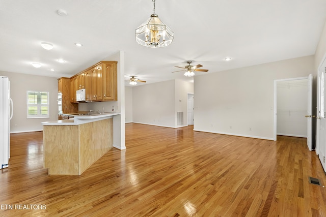 kitchen with light hardwood / wood-style floors, white appliances, kitchen peninsula, and hanging light fixtures