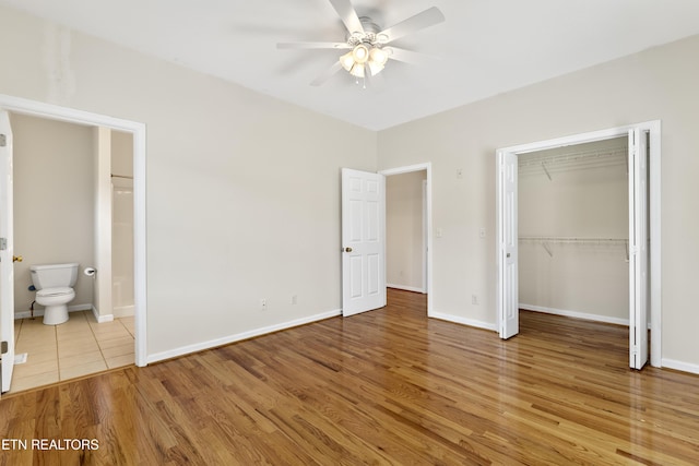 unfurnished bedroom with ceiling fan, light hardwood / wood-style floors, a closet, and ensuite bath