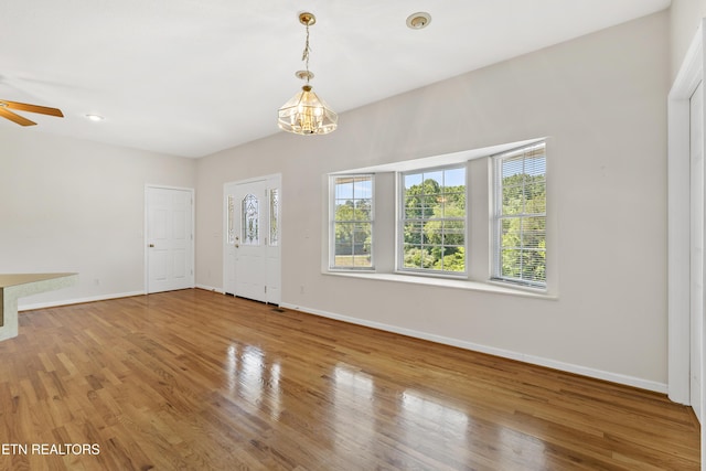 interior space with wood-type flooring and ceiling fan with notable chandelier