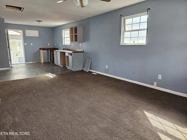 kitchen featuring ceiling fan, a textured ceiling, and dark carpet